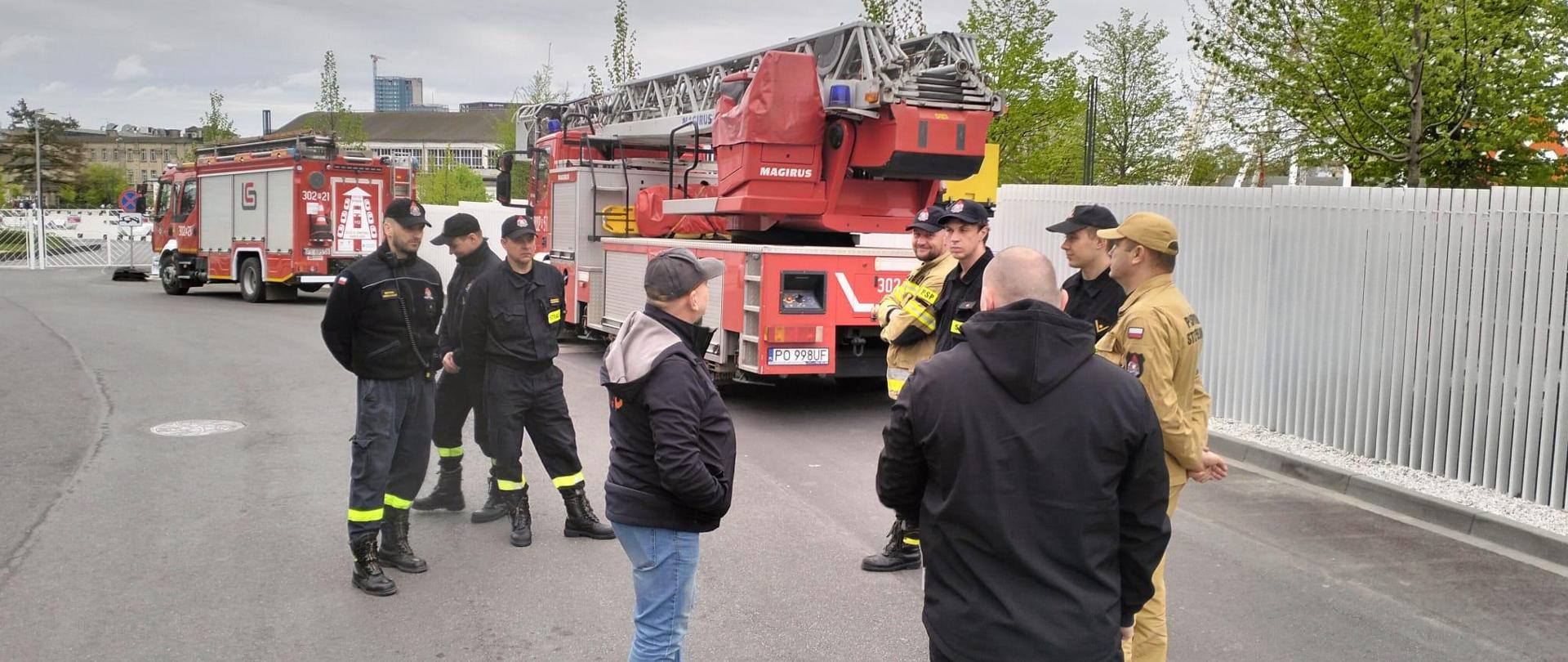 Na zdjęciu widzimy strażaków oraz pracowników MTP omawiających zmiany, które miały miejsce na terenie targów