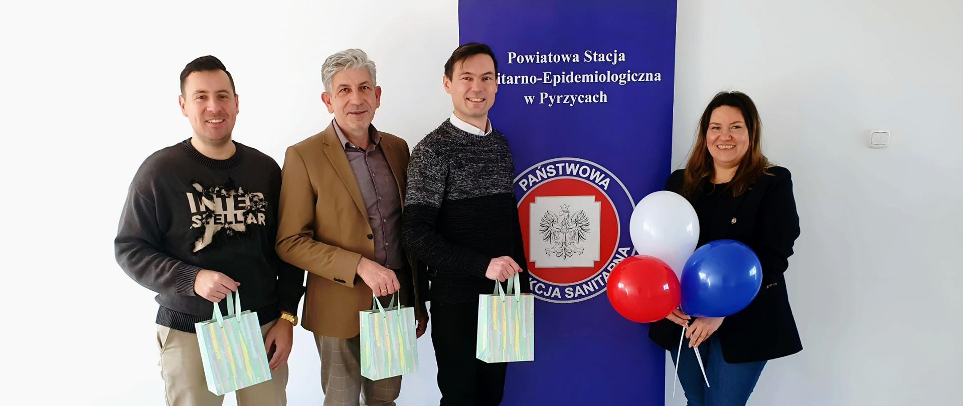 Zdjęcie przedstawia Państwowego Powiatowego Inspektora Sanitarnego w Pyrzycach wraz z pracownikami Powiatowej Stacji Sanitarno-Epidemiologicznej w Pyrzycach na tle firmowego baneru z logo Państwowej Inspekcji Sanitarnej.