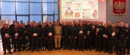 
Na zdjęciu grupowym strażacy Państwowej Straży Pożarnej z Małopolski w ubraniach dowódczo sztabowych na sali konferencyjnej podczas podsumowania projektu powietrze dla rot.