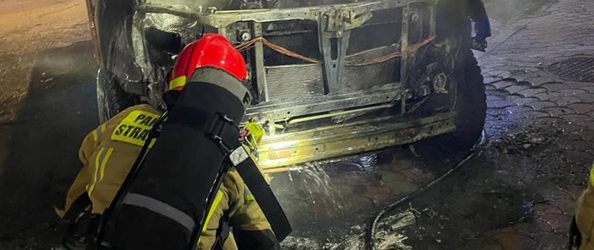 Strażak gasi pożar samochodu osobowego