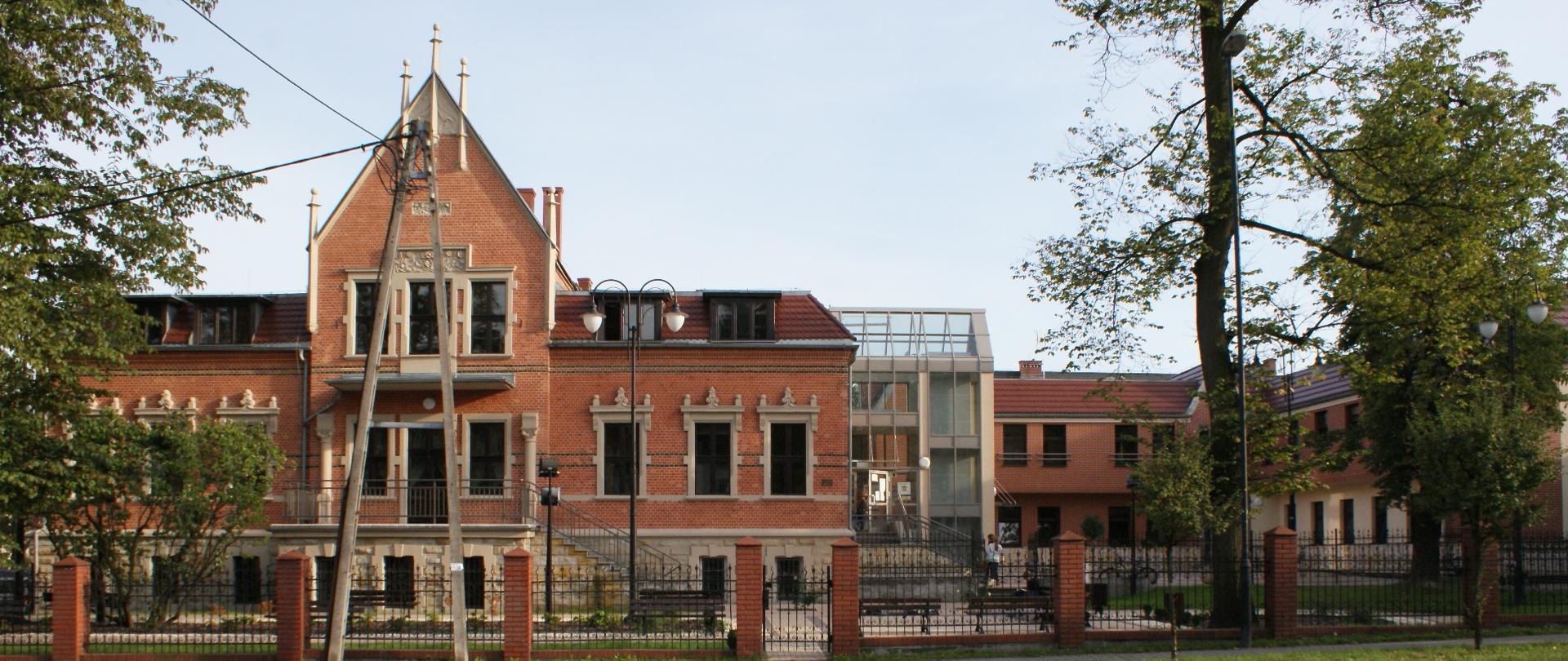 Na zdjęciu widoczna fasada główna budynku ZPSM wraz z ulicą Dworcową na pierwszym planie.