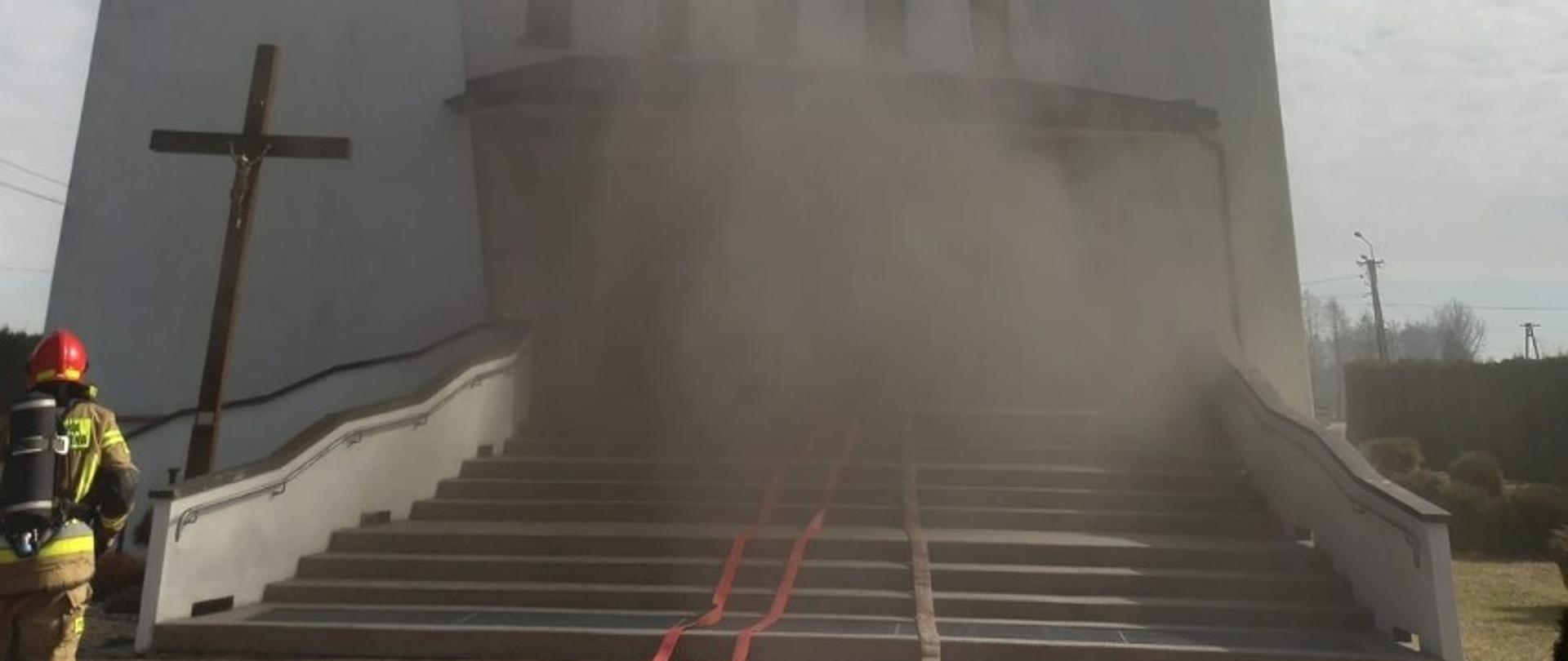 Na zdjęciu Kościół i strażak wchodzący do środka