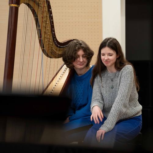 zdjęcie zdjęcie przedstawia dwie uczennice przy harfie na scenie sali koncertowej