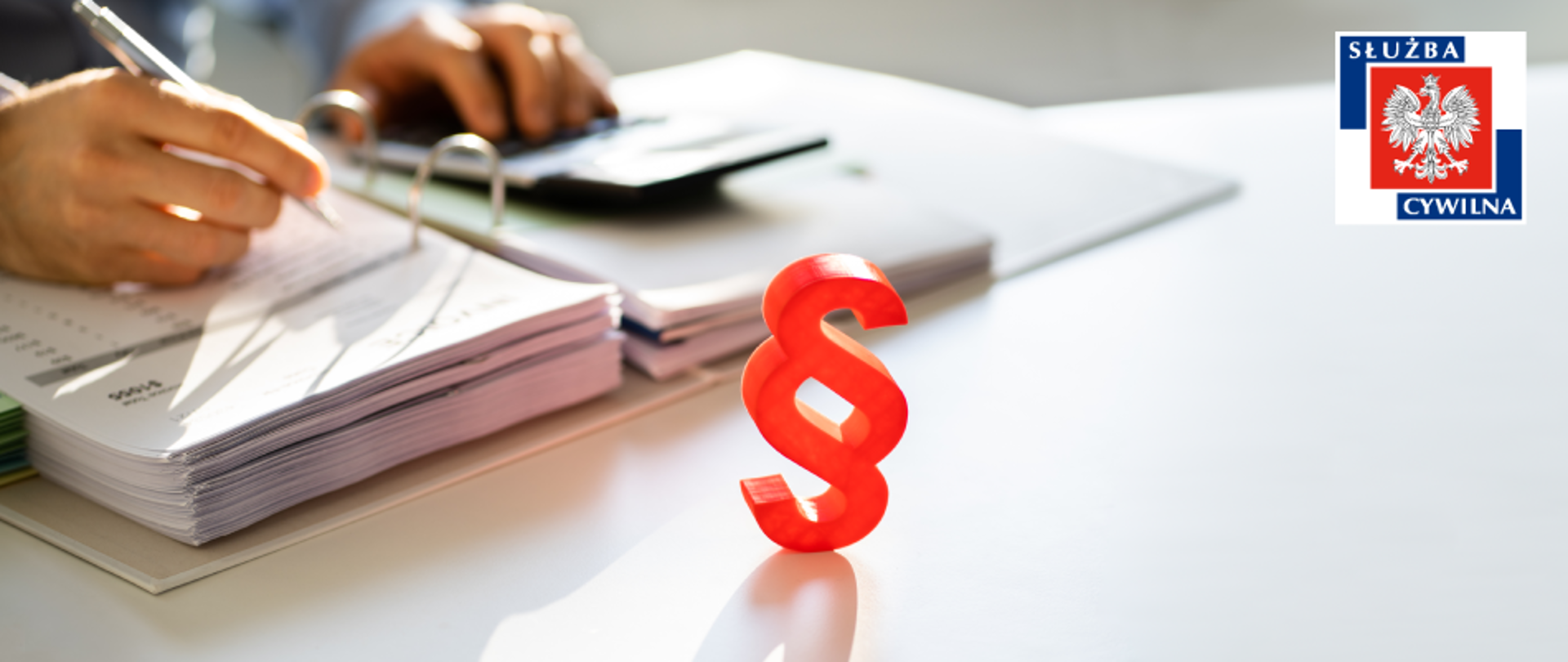 Ręka podpisująca dokument, w rogu logo służby cywilnej