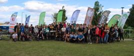 Grupowe zdjęcie uczestników SAR Schools Adventure Race na tle banerów organizatorów i sponsorów.
