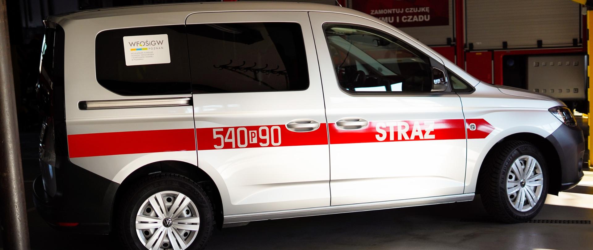 Samochód w kolorze srebrnym. Zdjęcie z boku pojazdu zrobione w garażu strażnicy.