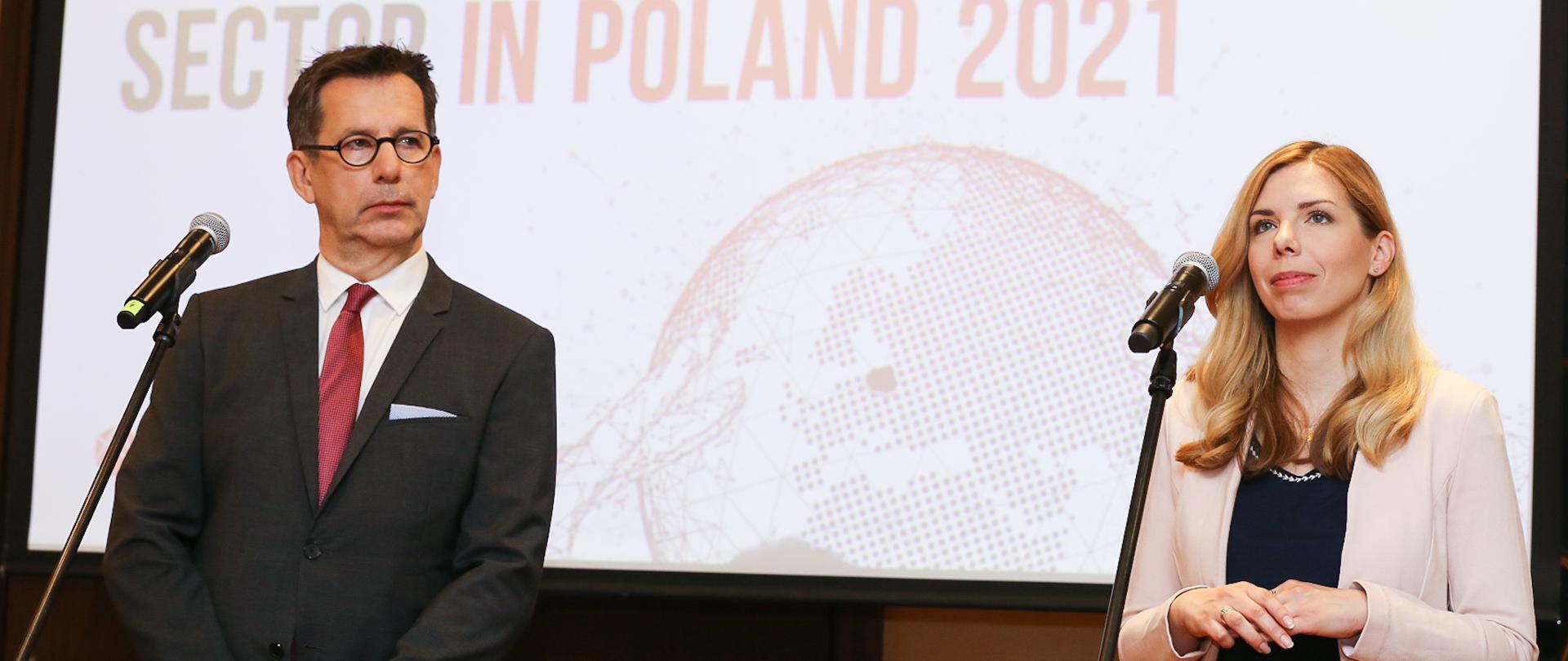 Wiceminister Anna Kornecka przemawia na tle ekranu podczas konferencji prasowej. Na ekranie widoczne logo wydarzenia.