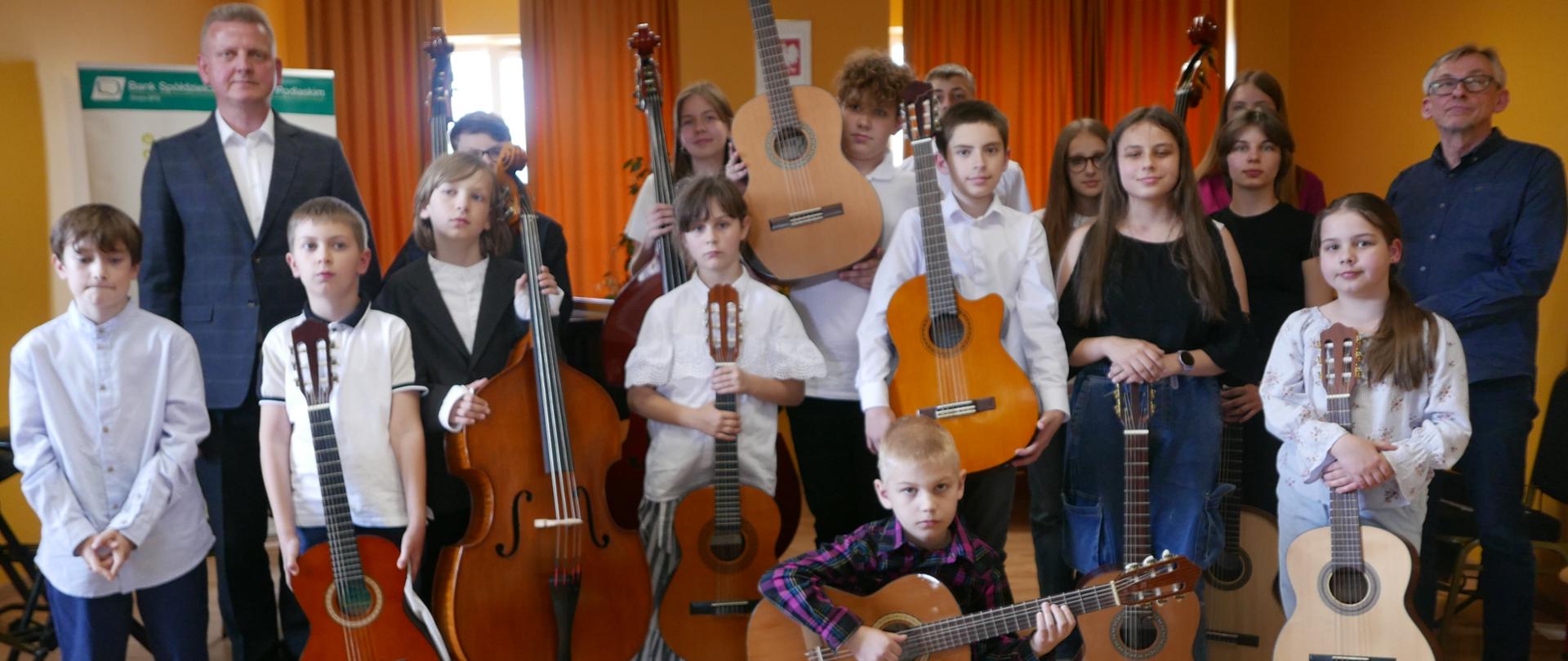 Na zdjęciu widzimy gitarzystów i kontrabasistów, część z nich trzyma instrumenty na których grali. Widzimy również nauczycieli kontrabasu i gitary.