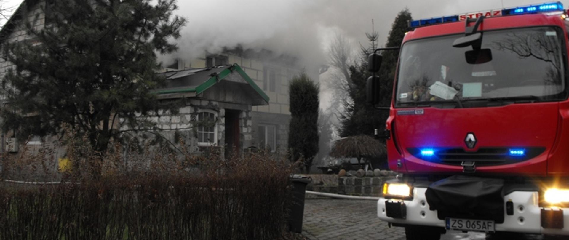 Zdjęcie przedstawia samochód gaśniczy przed palącym się budynkiem