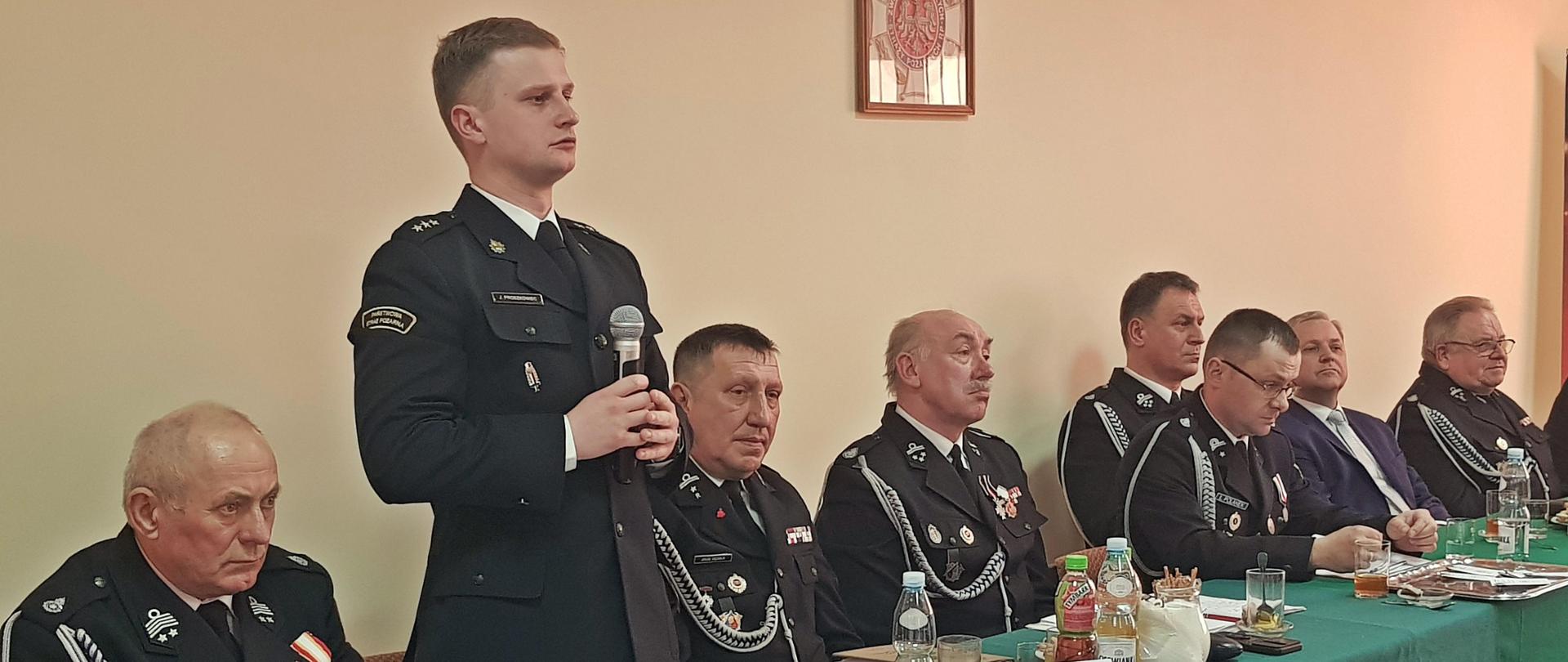 Prezydium zebrania - członkowie Zarządu OSP i zaproszeni goście za stołem prezydialnym.