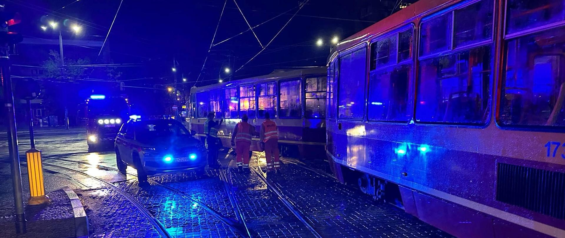 Dwa tramwaje stojące na torowisku obok dwa samochody pożarnicze 