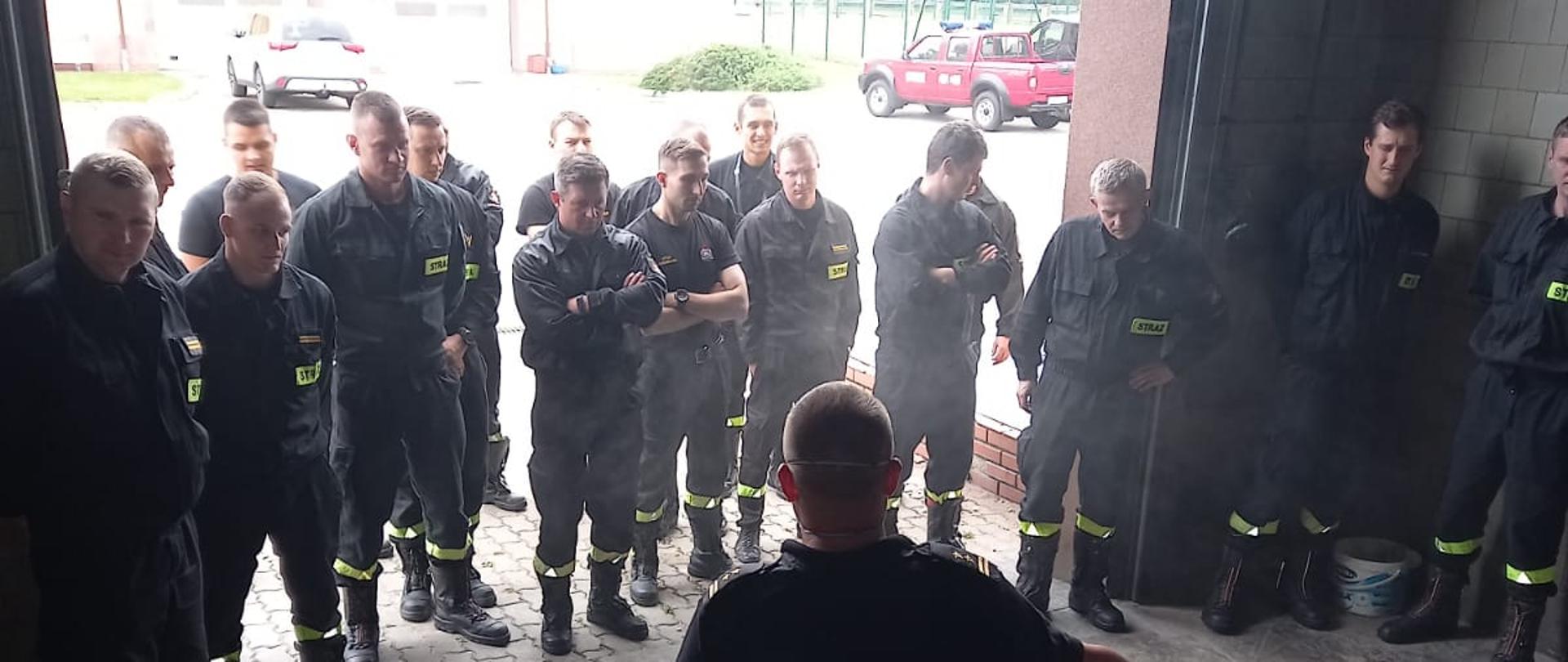 Widoczni strażacy w garażu, w tle plac, w skrzynkach na podłodze butelki z chemikaliami