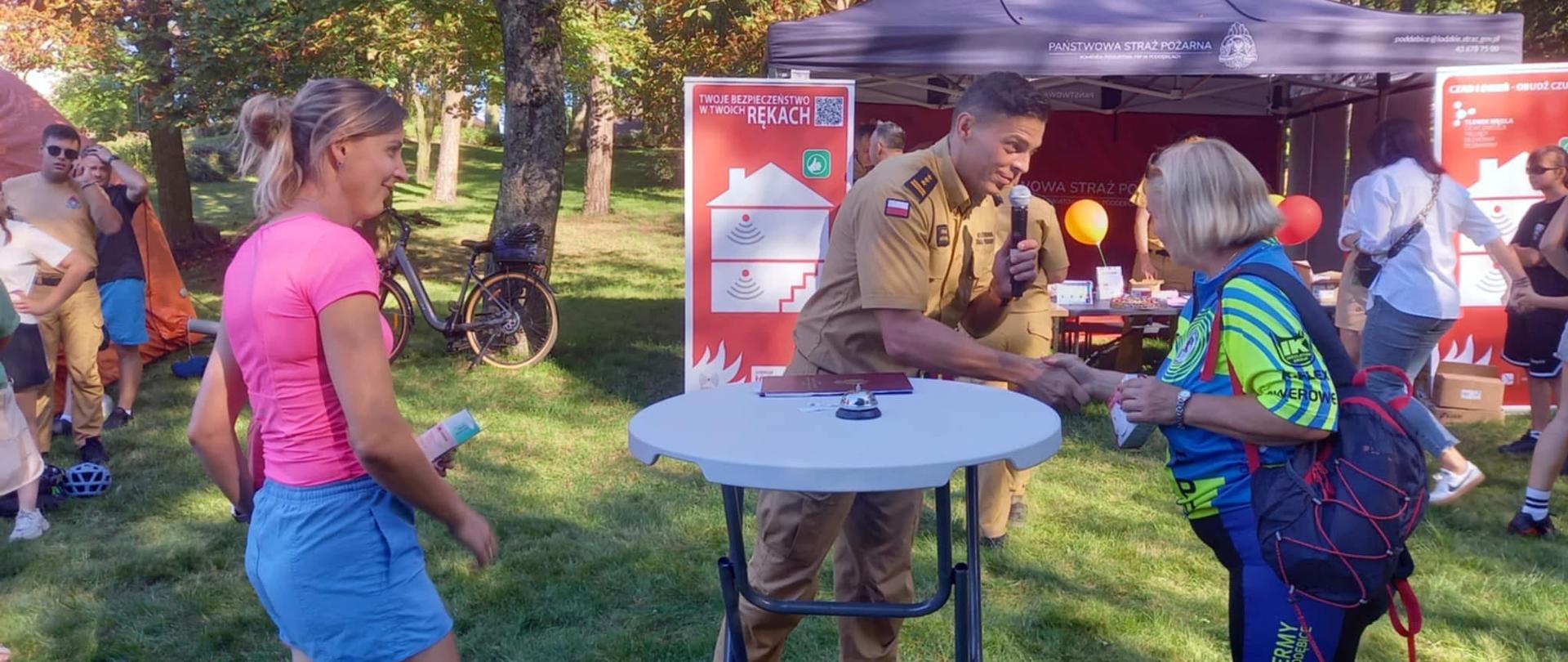 strażak wręcza czujkę kobiecie