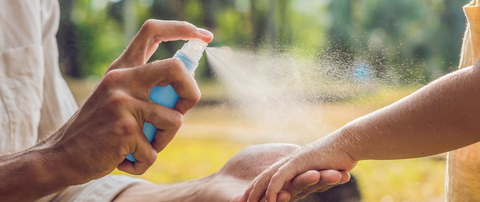 Osoba dorosła pryska aerozol na dłonie dziecka