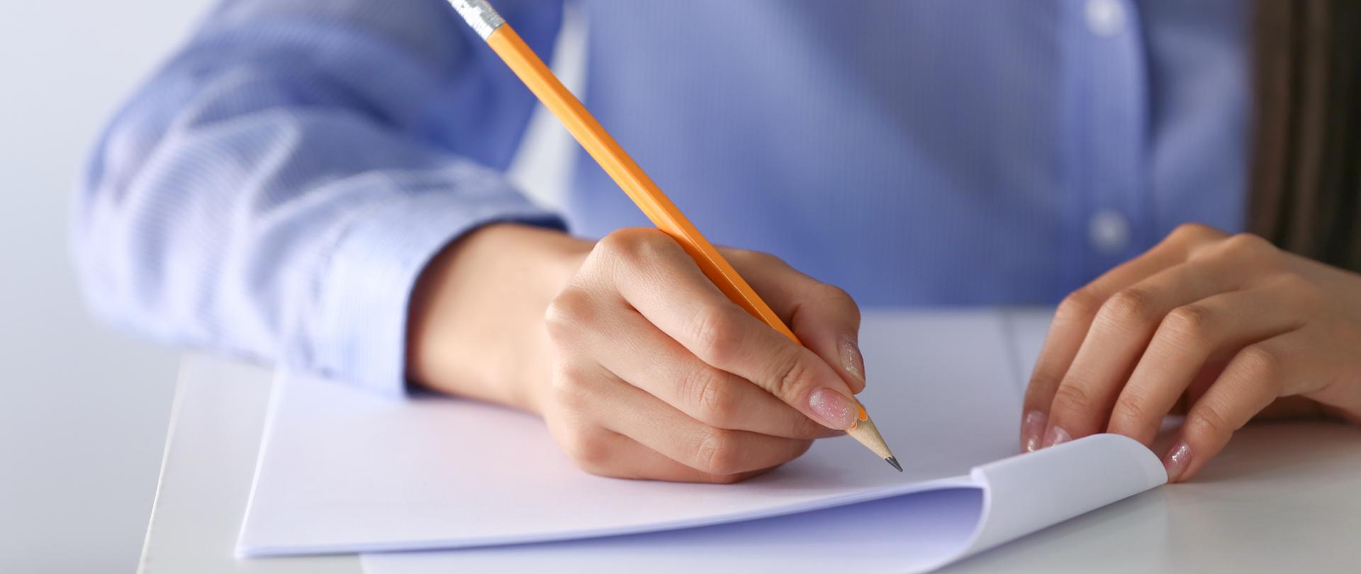 Young female student writing on sheet of paper, closeup