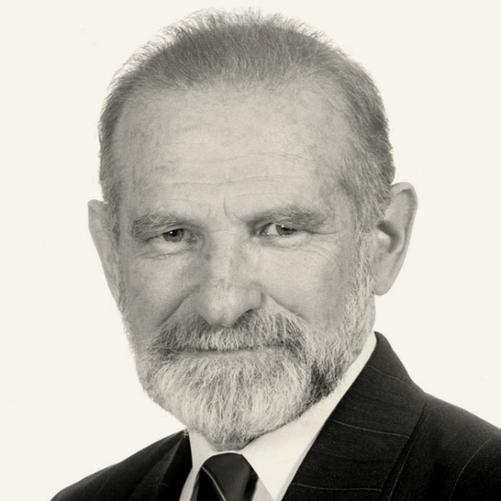 Bronisław Geremek - czarno - biały portret mężczyzny, siwe włosy, broda, ciemna marynarka w paski, krawat w paski, biała koszula.