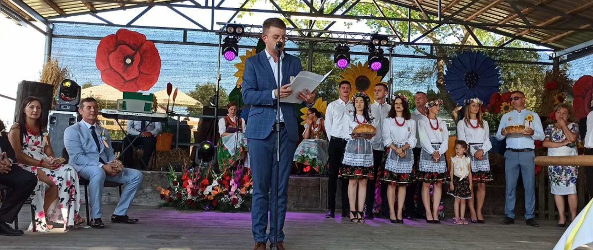 Na scenie mężczyzna odczytuje list – w tle inne osoby.