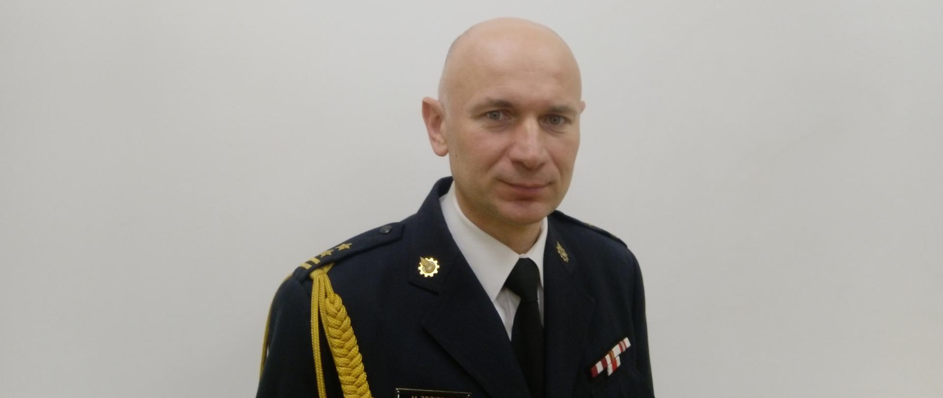 Komendant Miejski PSP w Żorach bryg. Marek Zdziebło w mundurze wyjściowym w białej koszuli pod krawatem ustawiony na białym tle. Zdjęcie portretowe z prawym ramieniem zwróconym lekko do przodu