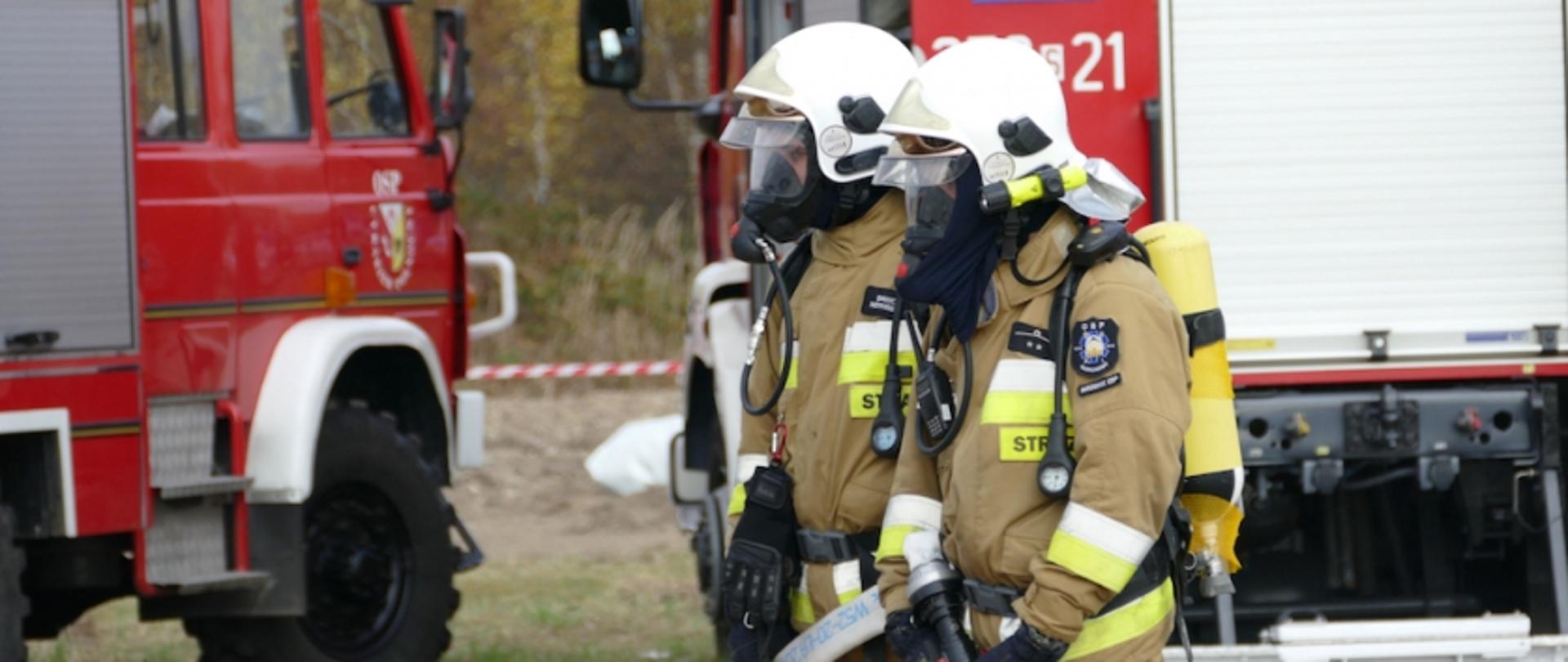 Strażacy OSP na tle czerwonych samochodów bojowych