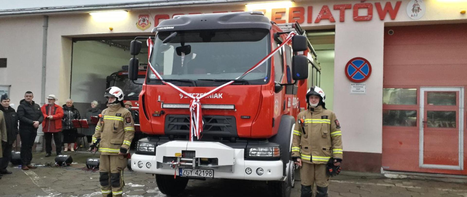 Widoczni na zdjęciu druhowie z OSP Trzebiatów przy nowym wozie bojowym Renault, w tle remiza