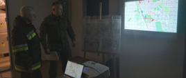 Współdziałanie z WOT. Stanowisko dowodzenia. Żołnierz dowodzący operacją zapoznaje zastępcę komendanta powiatowego PSP z terenem działań - prezentując mamy taktyczne.