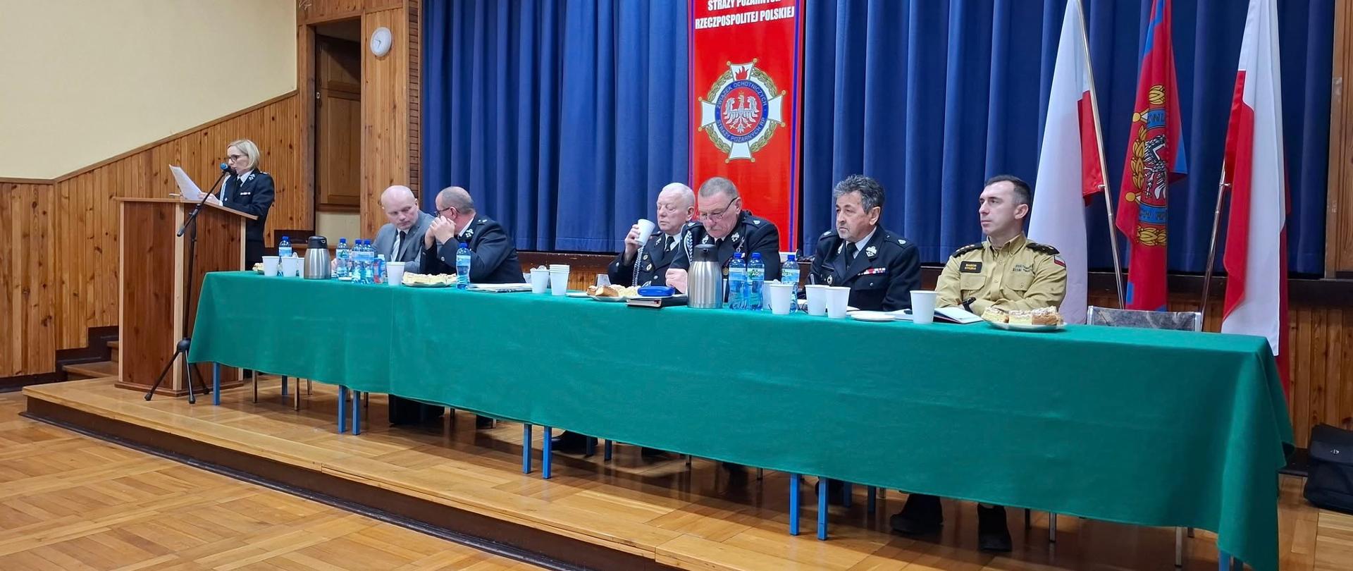 Druhowie oraz zaproszone osoby siedzą przy stole.