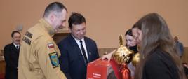 Na zdjęciu Komendant Powiatowy PSP w Oleśnie oraz Starosta Oleskie wręcza nagrody dzieciom. 