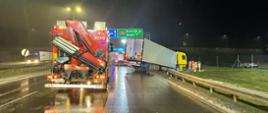 Zdjęcie przedstawia samochód ciężarowy z naczepą, który przerwał barierę energochłonną i zatrzymał się w rowie na autostradzie A2 w kierunku Poznania. Na zdjęciu widać również samochody strażackie. 