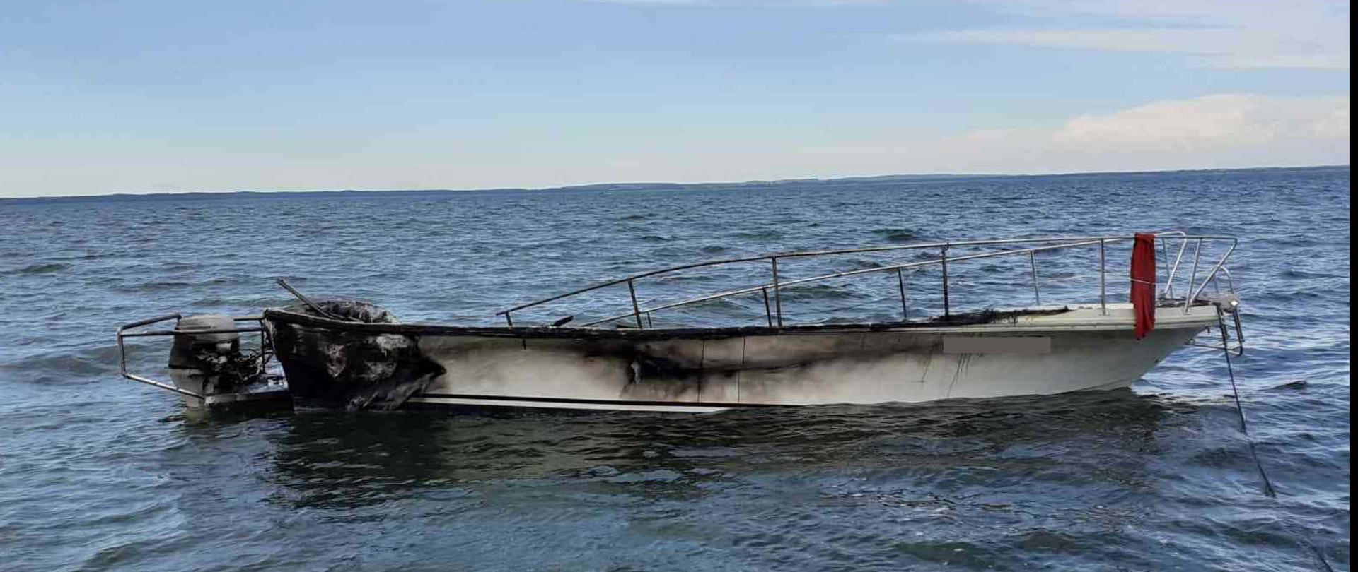 Spalona motorówka holowana do brzegu.