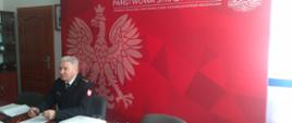 Komendant Powiatowy PSP na tle ścianki prezentacyjnej KP PSP w Ostrowie Wielkopolskim.