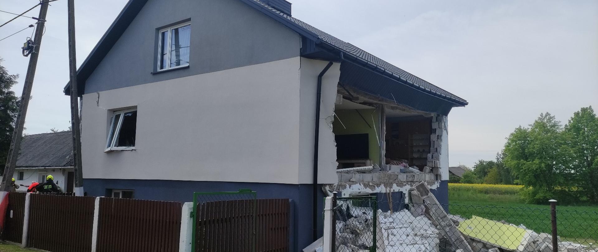 Na pierwszym planie budynek mieszkalny jednorodzinny, jedna ze ścian wypchnięta na zewnątrz utworzyła gruzowisko