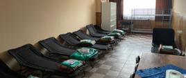 Pomieszczenie w którym znajdują się łóżka polowe oraz inne wyposażenie
