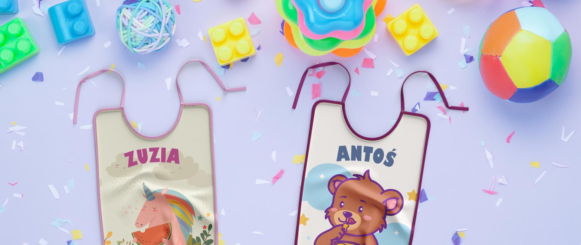 Zdjęcie - na fioletowym tle niemowlęce zabawki (piłka, klocki) oraz dwa śliniaczki. Na jednym z nich imię Zuzia, na drugim - Antoś.