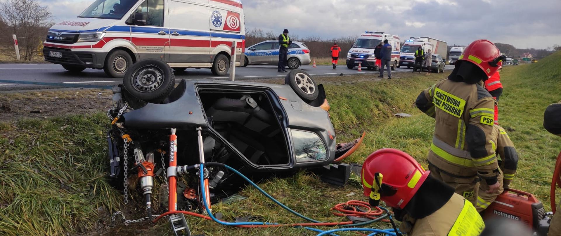 Samochód osobowy po dachowaniu z którego strażacy uwalniali kierowcę.