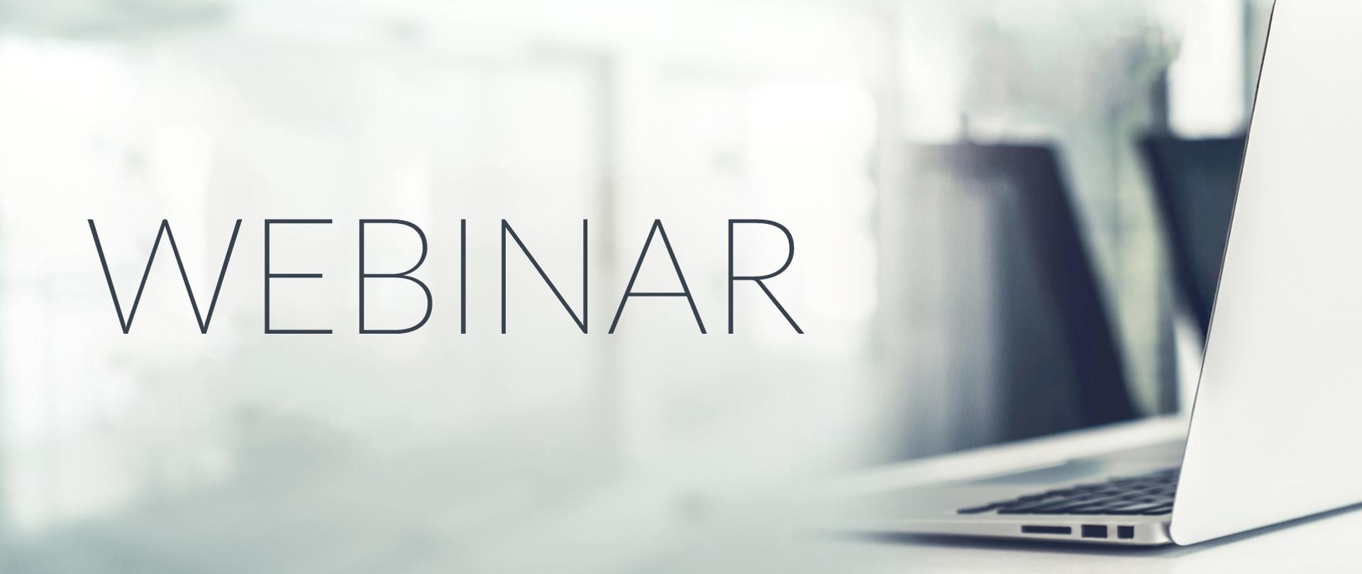 Napis „WEBINAR” na jasnym, rozmytym tle. Po prawej stronie widoczny fragment laptopa na biurku.