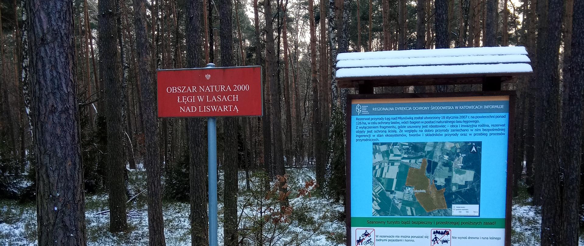 Tablica ustawiona w jednym z rezerwatów, w tle las pokryty śniegiem 