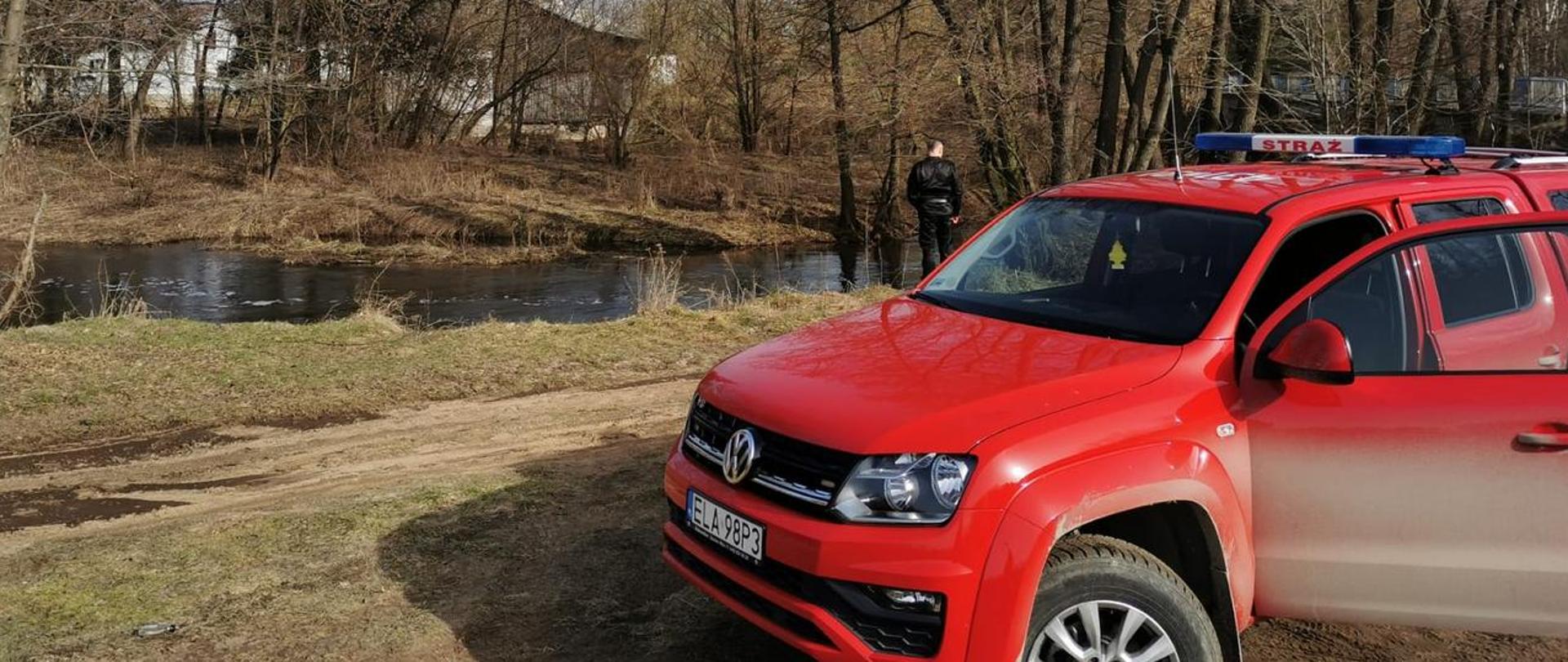 Zdjęcie przedstawia zaparkowany samochód operacyjny Państwowej Straży Pożarnej, podczas prowadzenia przez oficerów monitoringu zagrożenia powodziowego