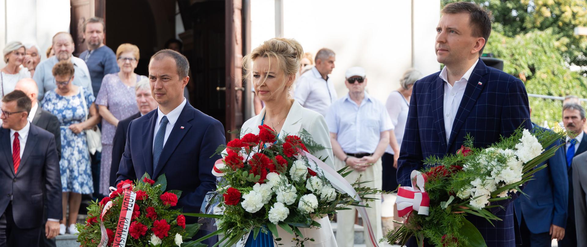 Kilka osób podczas składania kwiatów