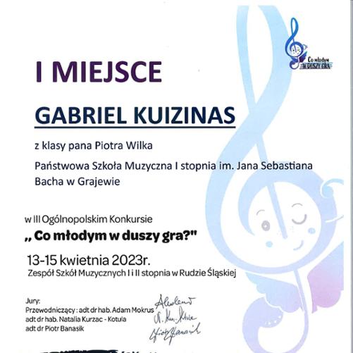 Dyplom w jasnych barwach a napisy w niebieskich: I miejsce Gabriel Kuizinas, poniżej z klasy pana Piotra Wilka, Państwowa Szkoła Muzyczna I stopnia im. Jana Sebastiana Bacha w Grajewie, poniżej w III Ogólnopolskim Konkursie "Co młodym w duszy gra" 13-15 kwietnia 2023r. Zespół Szkół Muzycznych I i II stopnia w Rudzie Śląskiej. Poniżej podpisy jury.