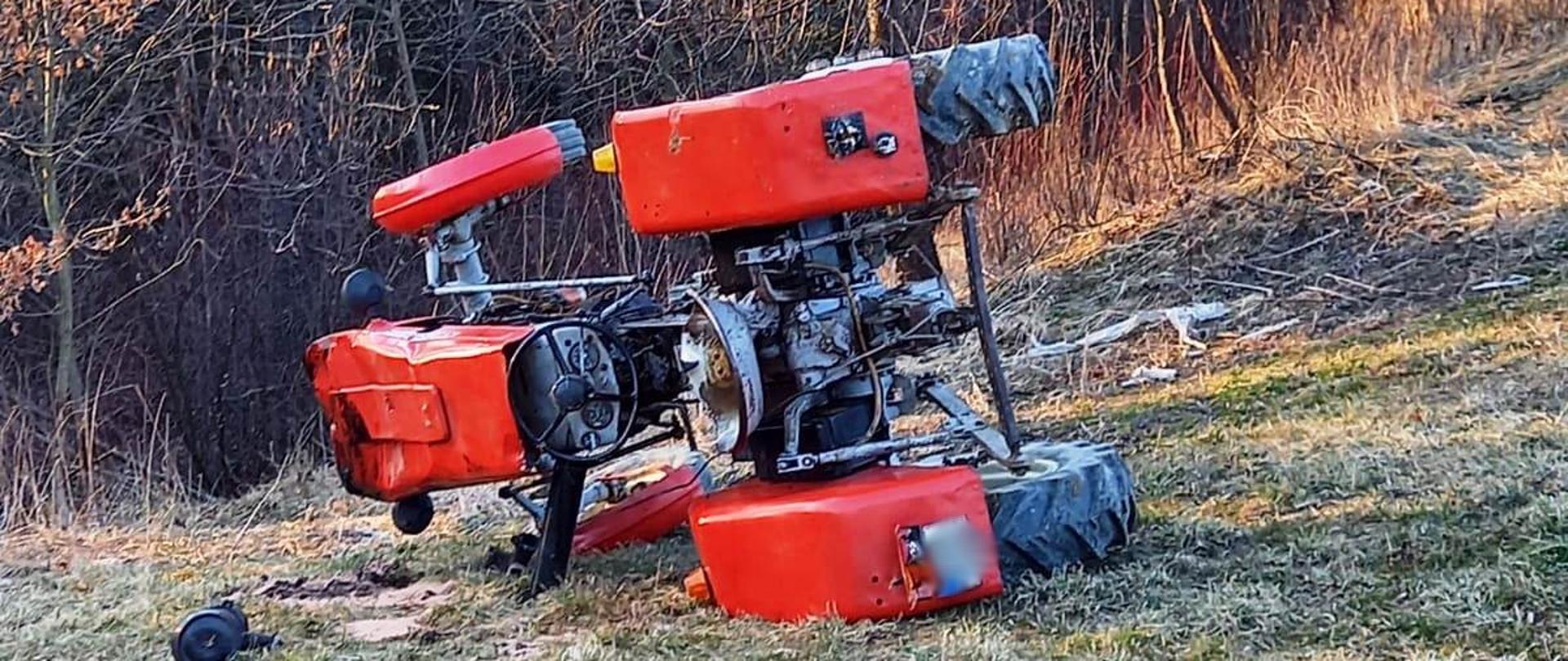 Ciągnik rolniczy leży na prawym boku na łące.