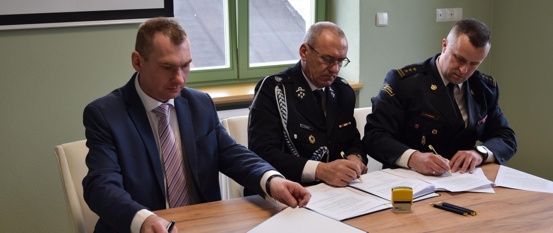 na zdjęciu widać przedstawiciela jednostki OSP, Komendanta PSP oraz Burmistrza miasta i gminy podczas podpisywania porozumienia