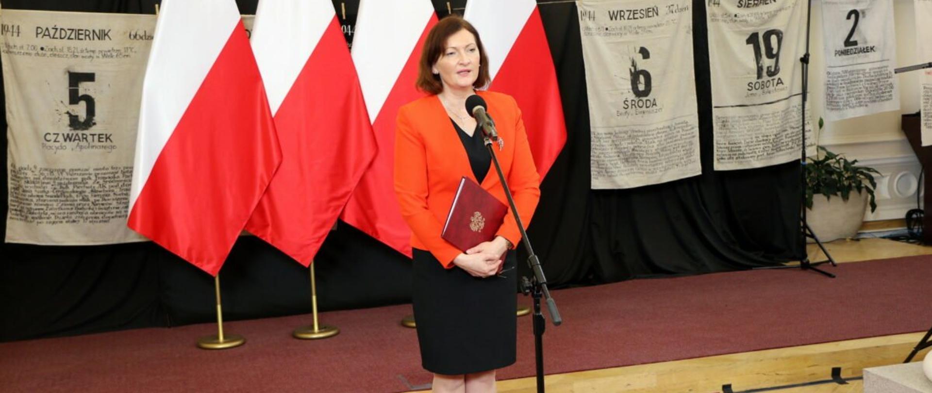 Wojewoda podkarpacki Ewa Leniart, stojąca na tle biało-czerwonych flag przemawia podczas Kongresu Osób Represjonowanych, Działaczy Solidarności i Kombatantów. 