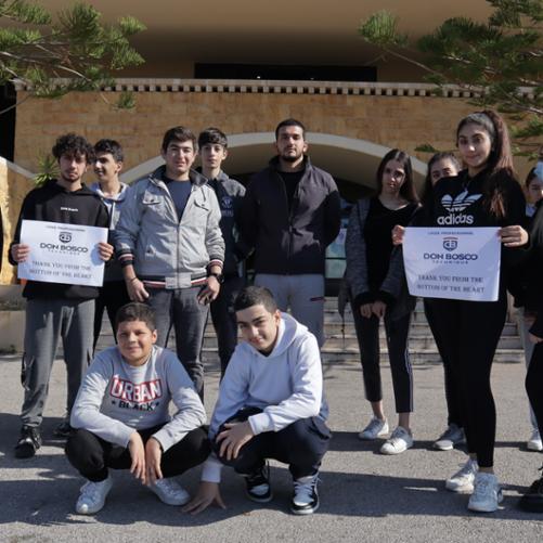 Na zdjęciu widać uczniów Salezjańskiej Szkoły Zawodowej, którzy są beneficjentami stypendium. Młodzież pozuje do zdjęcia. Dziewczyna i chłopak trzymają kartki na których widać napis: thank you from the bottom of the heart