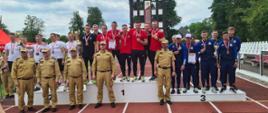 Na zdjęciu na podium stoją zwycięskie drużyny, przed nimi komendanci