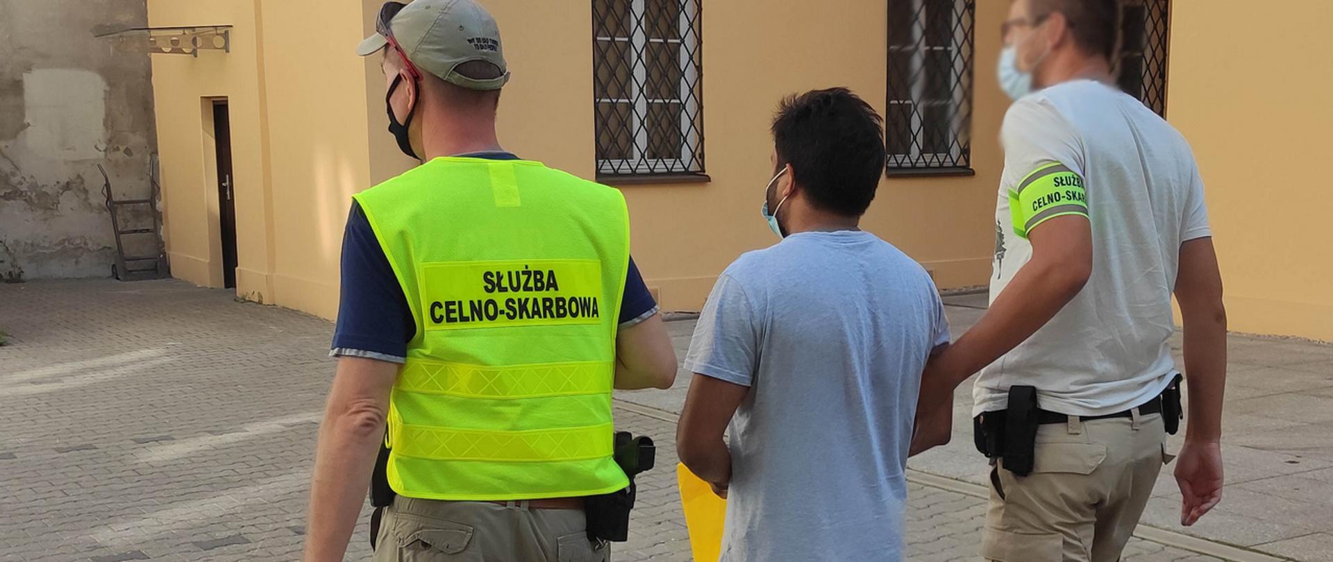 Dwaj funkcjonariusze prowadzą mężczyznę, który został zatrzymany