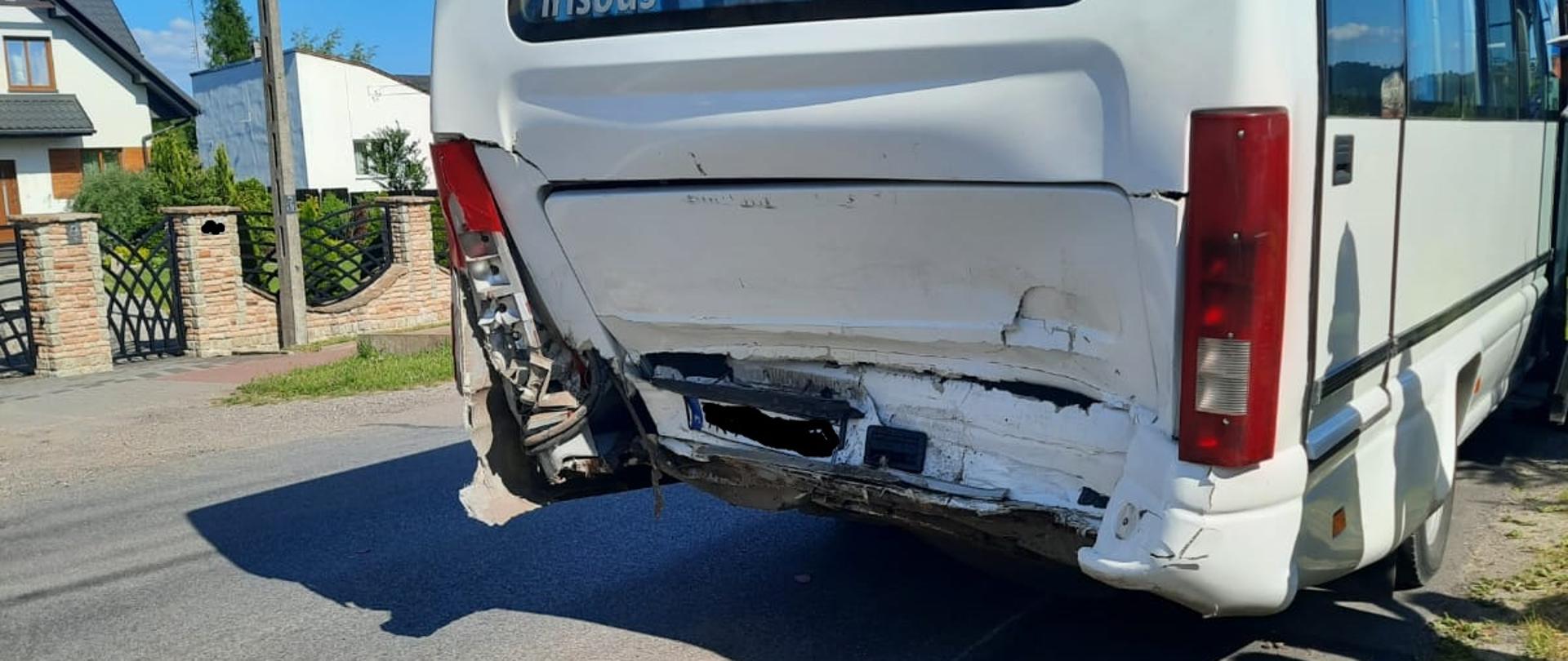 Na zdjęciu widać uszkodzony tył busa kursowego marki Iveco. W tle widać budynki mieszkalne.
