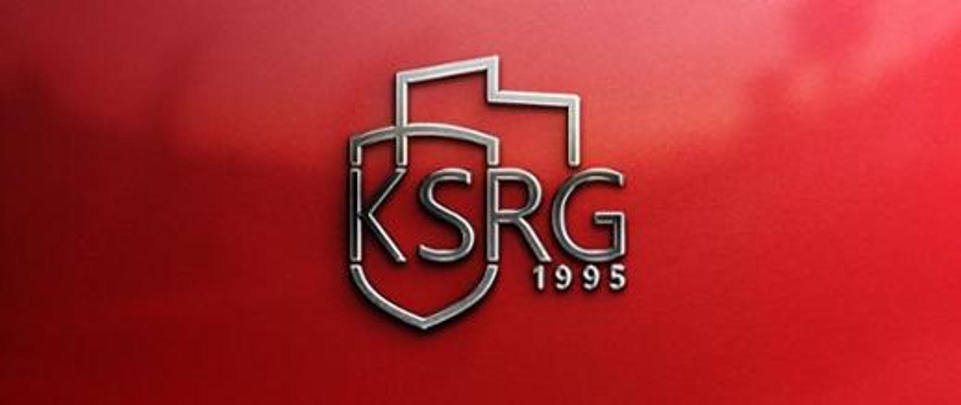 Zdjęcie przedstawia napis drukowanymi literami KRSG 1995 na czerwonym tle
