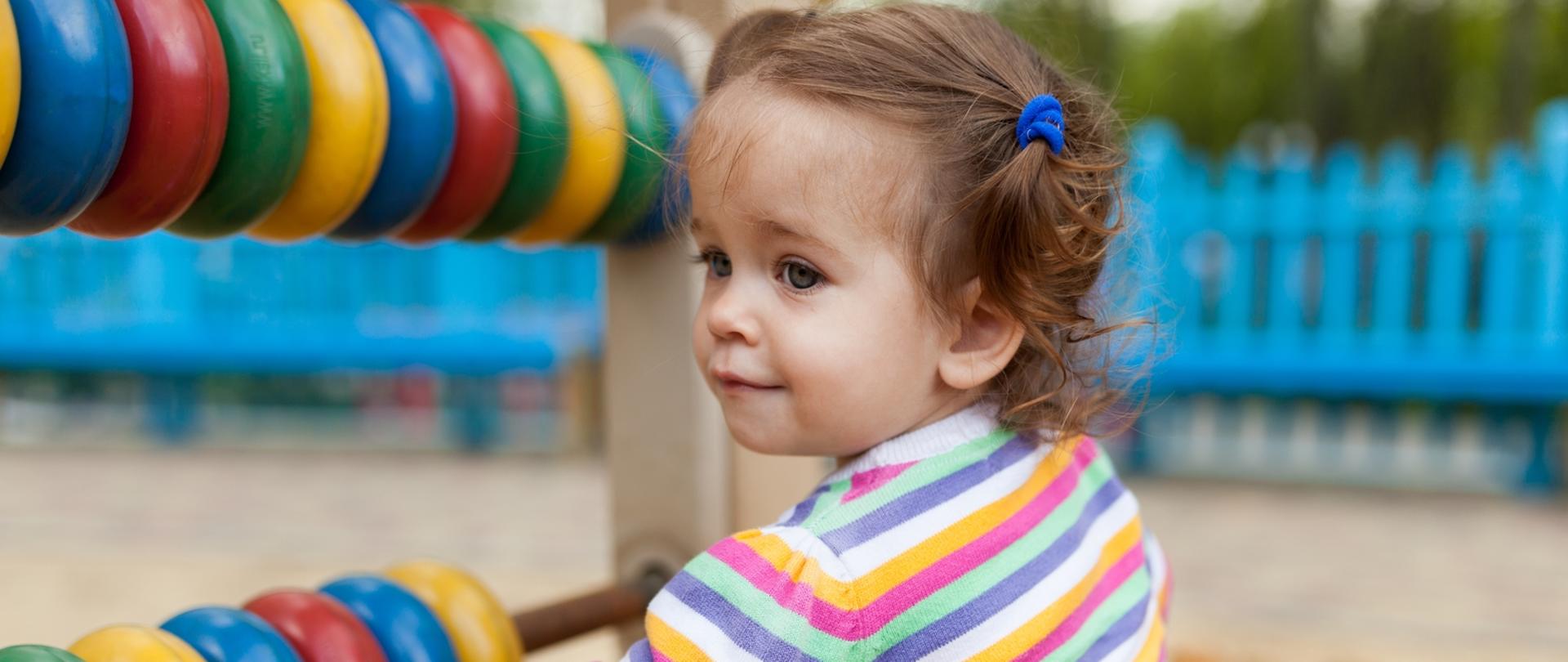 Zdjęcie przedstawia dziewczynkę bawiącą się na placu zabaw