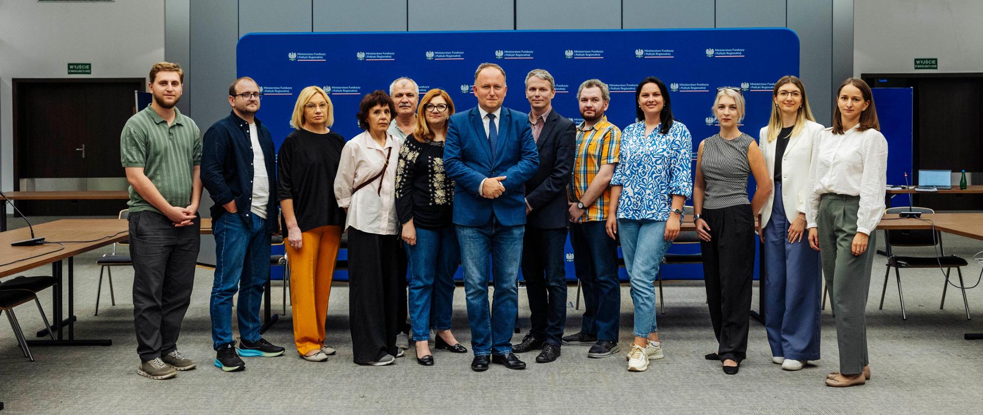 Grupa osób stoi obok siebie.