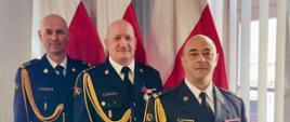 Od lewej: bryg. Sławomir Grudziński - Komendant Miejski PSP w Toruniu, st.bryg. Rafał Świechowicz - Kujawsko-Pomorski Komendant Wojewódzki PSP, mł. bryg. Grzegorz Miklaszewski - powołany na Zastępcę Komendanta Miejskiego PSP w Toruniu. Komendanci w umundurowaniu wyjściowym, w tle flagi państwowe.
